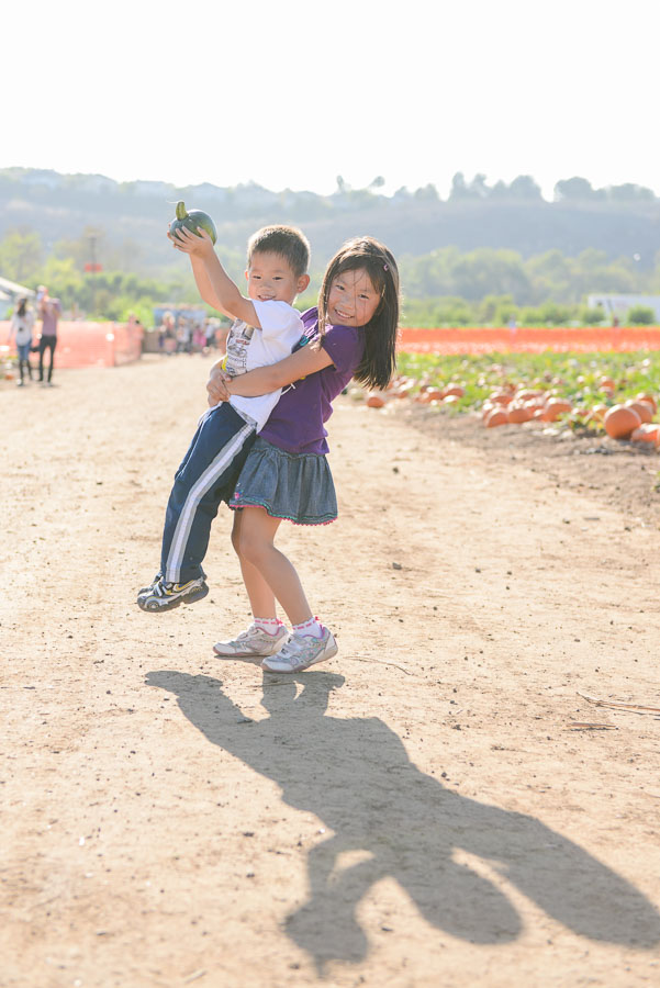 Lifting her little brother and his green pumpkin.