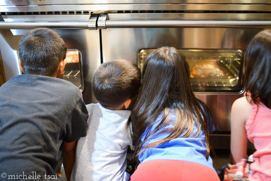 Anxiously waiting and watching the pizzas bake.