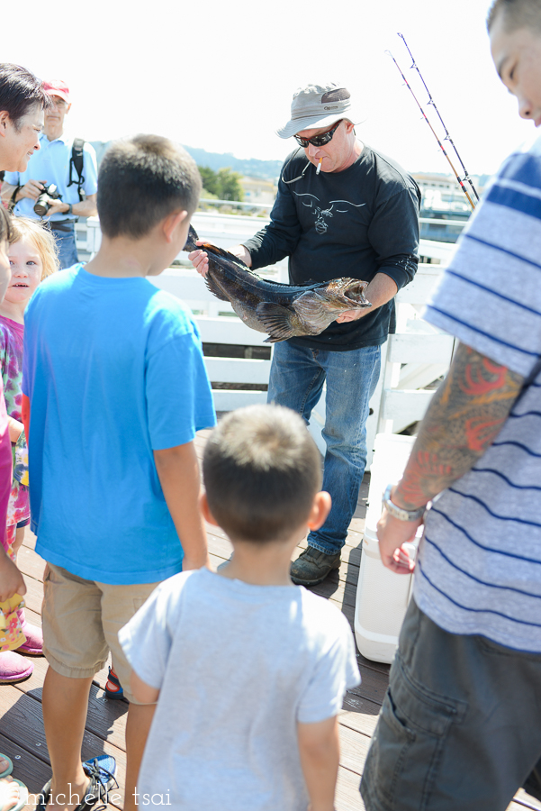 This gruff looking fisherman with cig dangling from his mouth showing off his catch of the day. Turned out to be a nice guy as he let one of the interested onlookers have a fish for free.